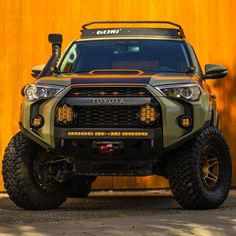 the front end of a four - doored toyota truck parked in front of a yellow wall