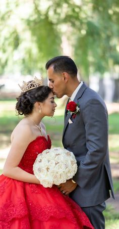 a man in a suit and tie kissing a woman in a red dress with a crown on her head