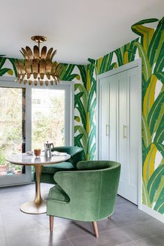 a living room filled with green furniture and walls covered in palm leaf wallpapers