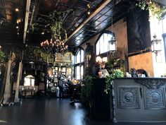 the inside of a restaurant with lots of plants hanging from the ceiling and chandeliers