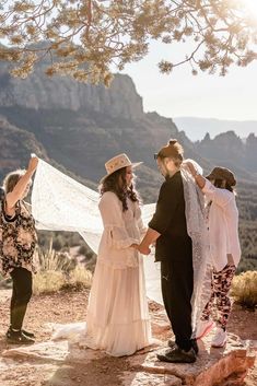 a group of people standing next to each other on top of a hill near mountains