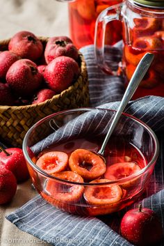 a bowl filled with sliced apples next to a basket of strawberries