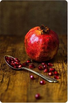 pomegranate and spoon on wooden table with dark background