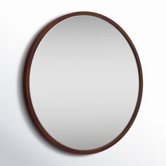 a round mirror hanging on the wall with a wooden frame and wood trim around it