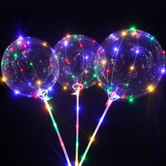 three clear balloons with lights on them in the dark