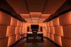 an empty room with orange lighting on the walls and a desk in the center surrounded by chairs