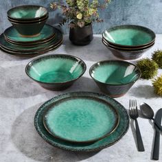 a table set with green dishes and silverware