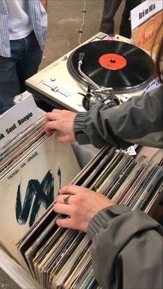 a person holding a record player in front of a table full of records and cds