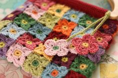 a crocheted purse with wooden handle on top of a flowery table cloth