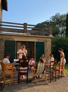 a group of people sitting around each other on lawn chairs in front of a building