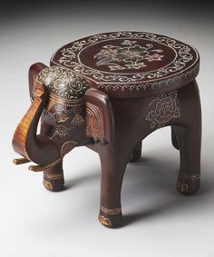 an elephant shaped wooden stool with intricate designs