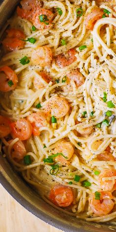 pasta with shrimp and parmesan cheese in a pan on a wooden table top