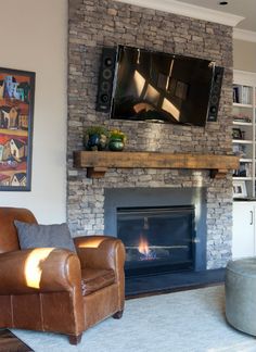 a living room with a couch, chair and television mounted on the brick fireplace mantel