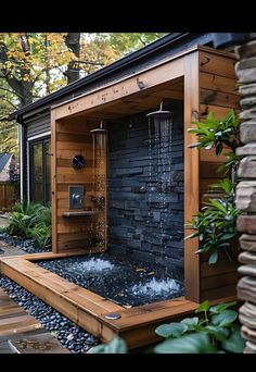 an outdoor shower with water coming out of it's side and surrounded by rocks