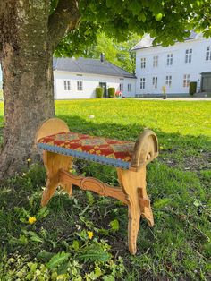 a wooden bench sitting under a tree in the grass