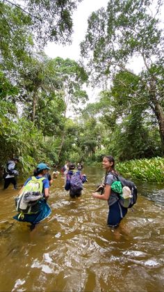 group of people walking through water with backpacks