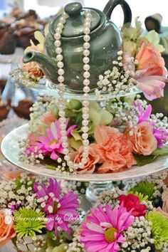 three tiered tray with flowers and a teapot on top