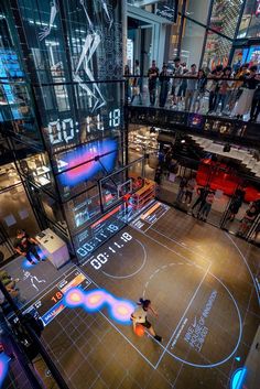 an indoor basketball court with people standing on the sidelines and watching it from above