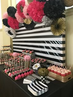 a black and white table topped with lots of cupcakes next to desserts