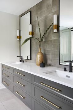 a bathroom with two sinks, mirrors and gold accents on the countertop in front of a large mirror