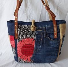 a handbag made out of jeans and fabric with a flower on the front pocket