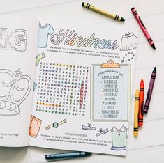 an open coloring book sitting on top of a table next to crayons and markers