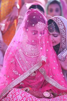 two women dressed in pink are sitting on the ground and one is holding another woman's head