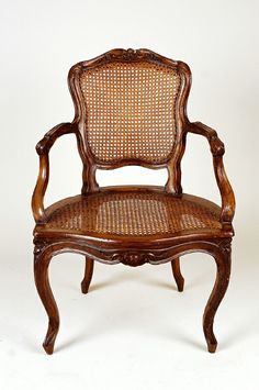 an old wooden chair with wicker back and arm rests against a plain white background