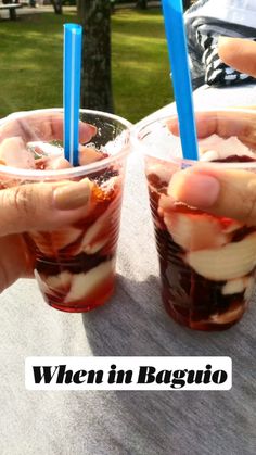 two people are holding their glasses with ice cream and jelly in them on a picnic table