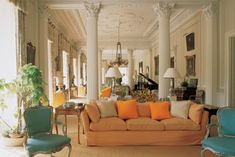 a living room with couches and chairs in it's center hall, surrounded by columns