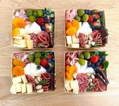 four square trays filled with different types of meat and cheese on top of a wooden table