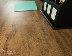 a wooden table with some pens and pencils on it, next to a binder