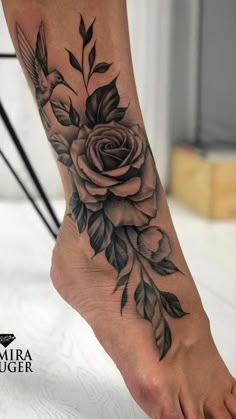 a rose and bird tattoo on the foot