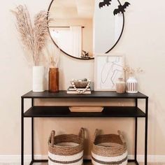 a black shelf with baskets under a round mirror on top of it next to plants and vases