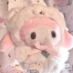 a white stuffed animal with a pink bow around its neck