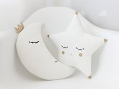 two white stars and a crescent pillow with eyes closed on a white surface in the shape of a moon