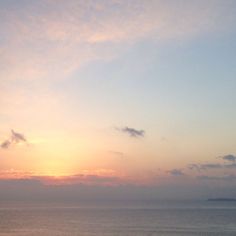 the sun is setting over the ocean with clouds in the sky