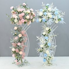 two vases with flowers are sitting on a white table and one is filled with blue and pink flowers