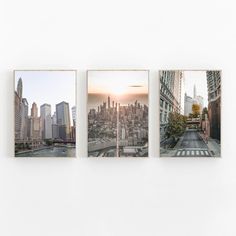 three pictures hanging on the wall with cityscape in the background and one is empty