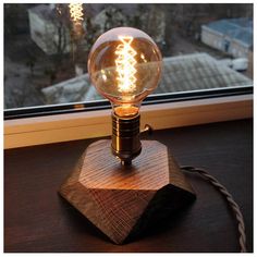 a light bulb sitting on top of a wooden block next to a window sill