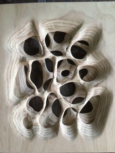 an intricately carved piece of wood sitting on top of a wooden table with holes in it