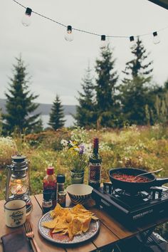 an outdoor table with food and drinks on it