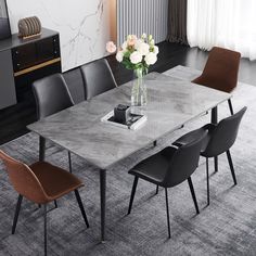 a dining room table with chairs and a vase filled with flowers on top of it