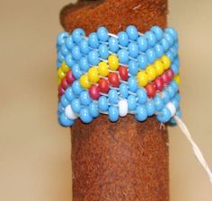 the beaded bracelet is on top of a brown tube with white and blue beads