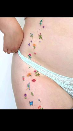 a woman's stomach with flowers and butterflies painted on the side of her belly