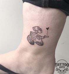 a small tattoo on the ankle of a woman's lower leg, depicting a dog riding a scooter