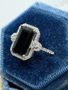 a black and white diamond ring sitting on top of a blue velvet box