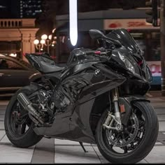 a black motorcycle parked in front of a building with lights on it's side