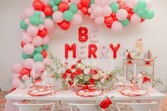 a table set up with balloons and flowers for a merry birthday party or baby's first birthday