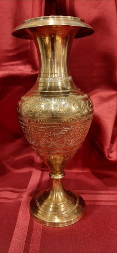 a gold vase sitting on top of a red cloth